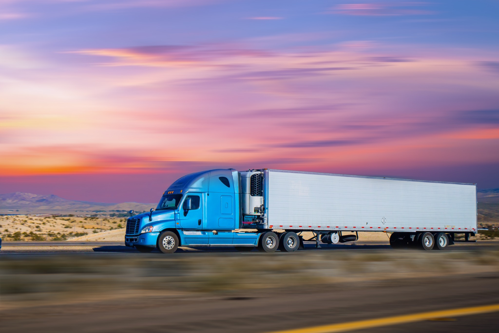 Blue semi truck at sunset